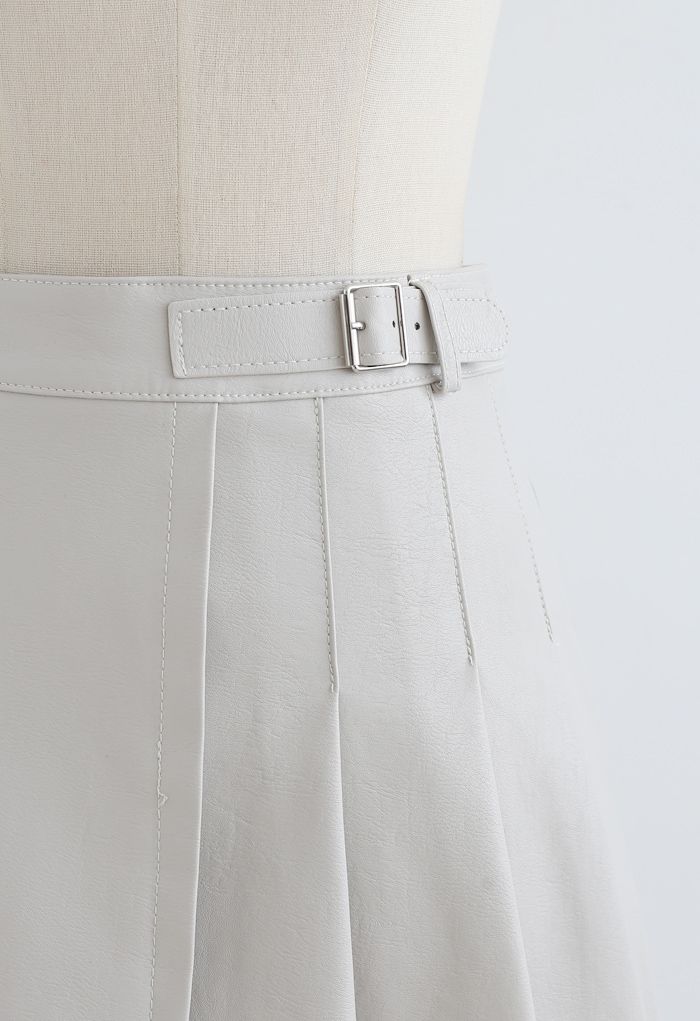 Minifalda plisada de piel sintética con detalle de cinturón en color crema
