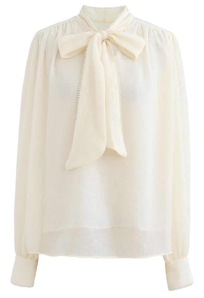 Camisa semitransparente con ribete de perlas y lazo en color crema