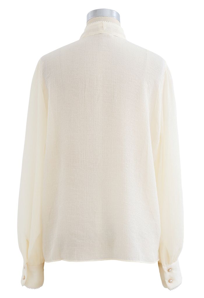Camisa semitransparente con ribete de perlas y lazo en color crema