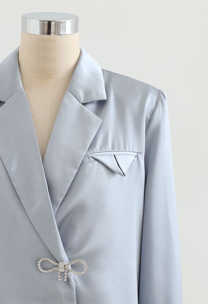 Camisa de satén con hombros acolchados con broche de cristal en azul