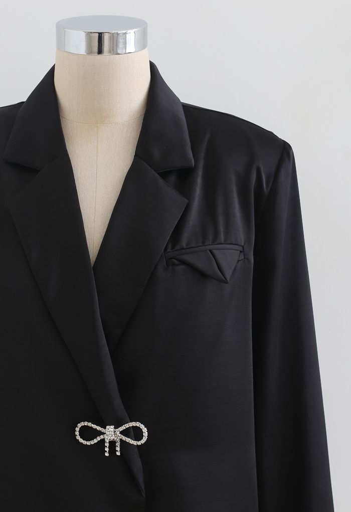 Camisa negra de satén con hombros acolchados con broche de cristal