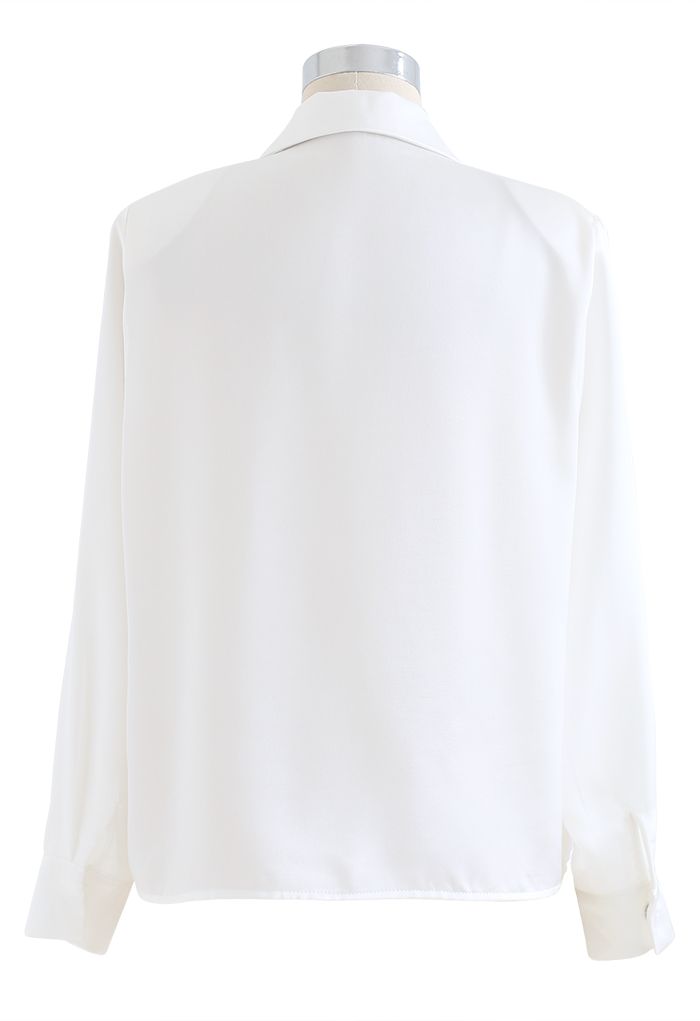 Camisa blanca de satén con hombros acolchados con broche de cristal