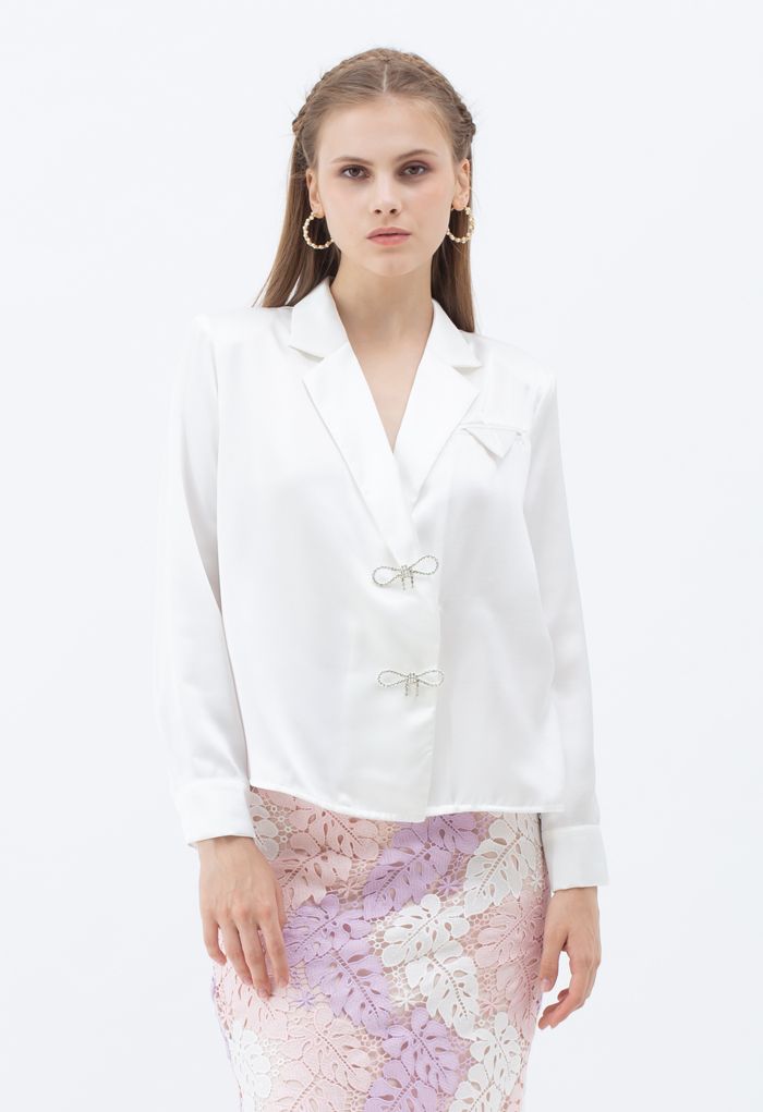Camisa blanca de satén con hombros acolchados con broche de cristal