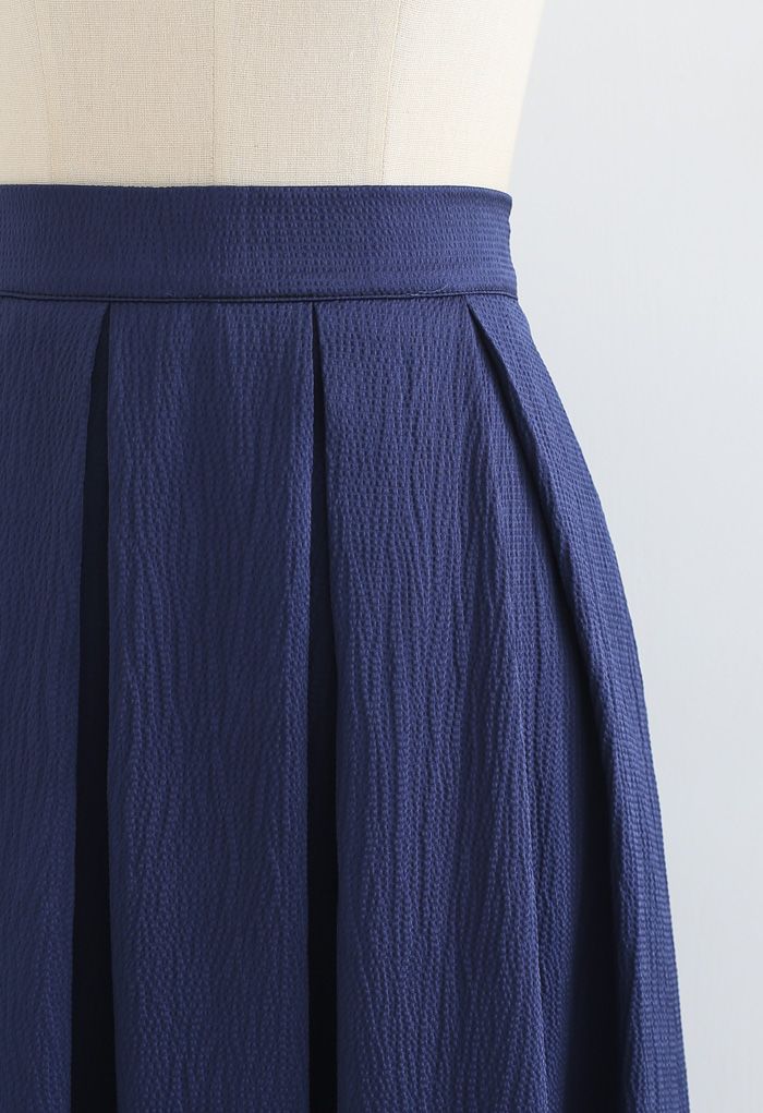 Falda midi plisada con textura pulida en azul marino