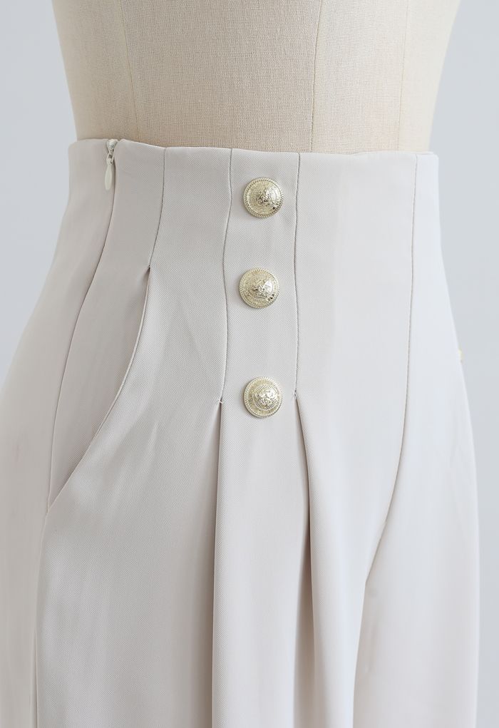 Pantalón plisado decorado con botones dorados en marfil