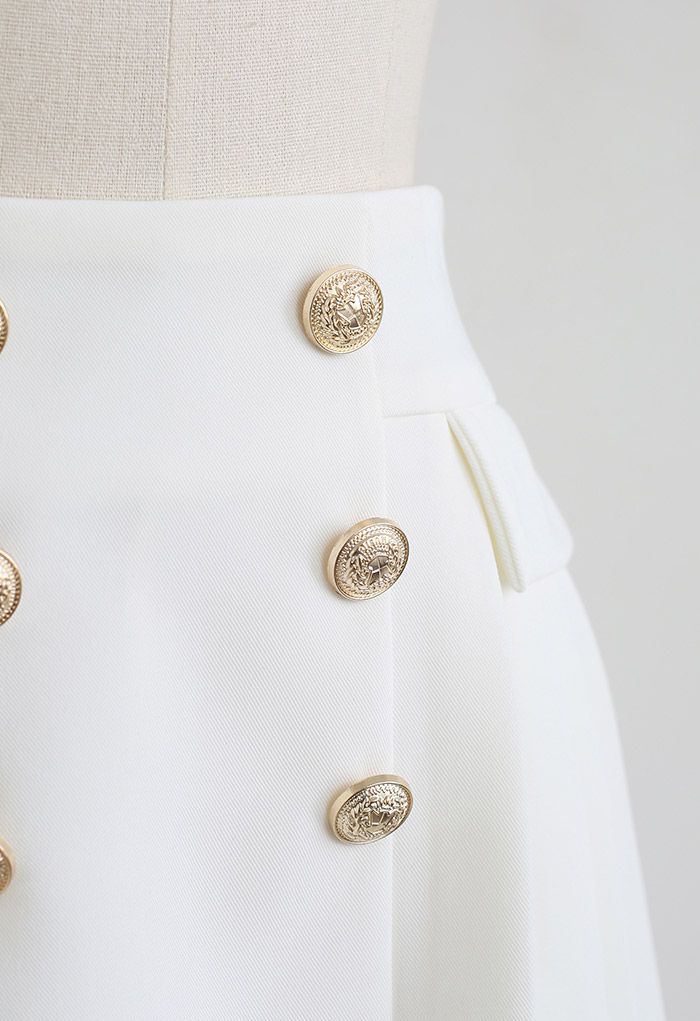 Minifalda plisada con sutiles botones dorados en blanco