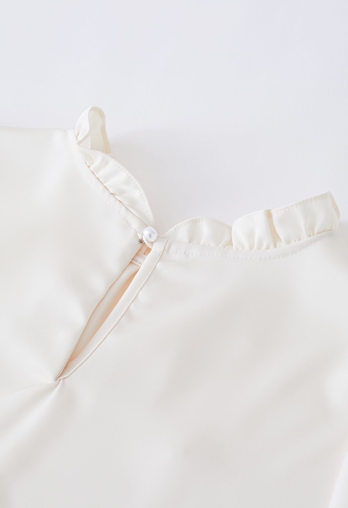 Camisa de satén adornada con perlas y escote con volantes en color crema