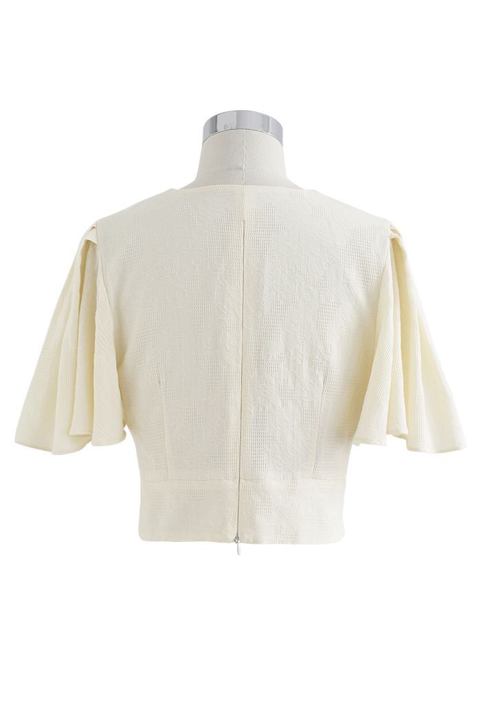 Top corto de algodón con mangas onduladas y parte delantera torcida en color crema