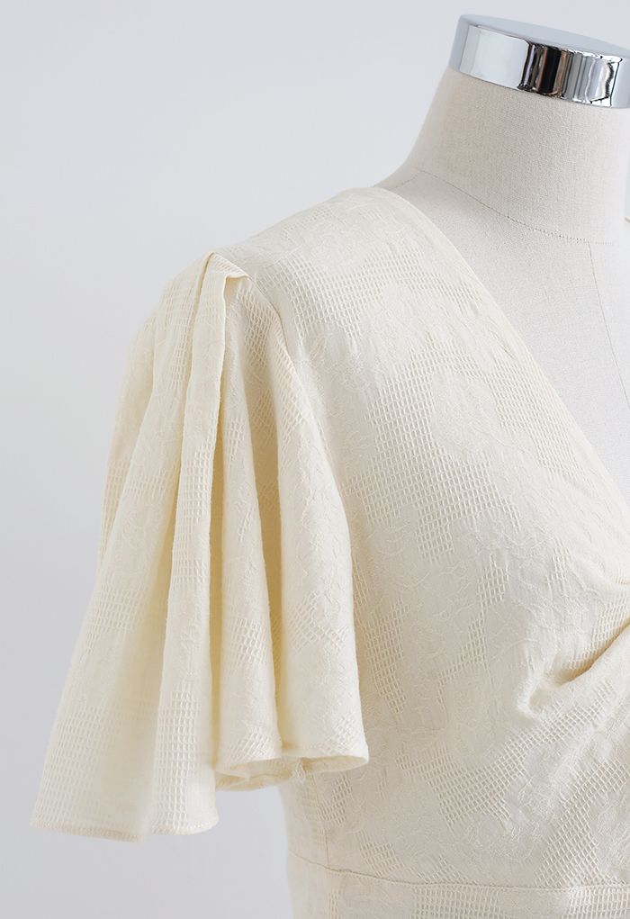 Top corto de algodón con mangas onduladas y parte delantera torcida en color crema