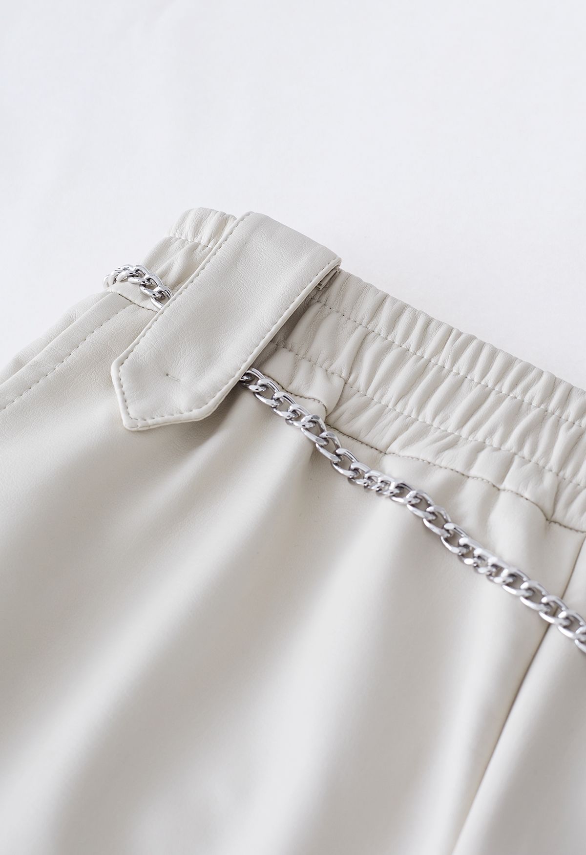 Shorts de cuero sintético con cadena plateada en marfil