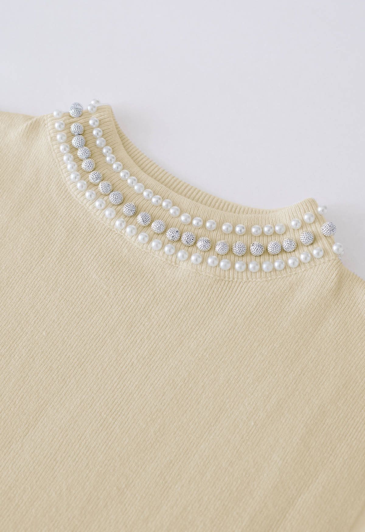 Top de punto sin mangas con cuello alto adornado con perlas en color arena