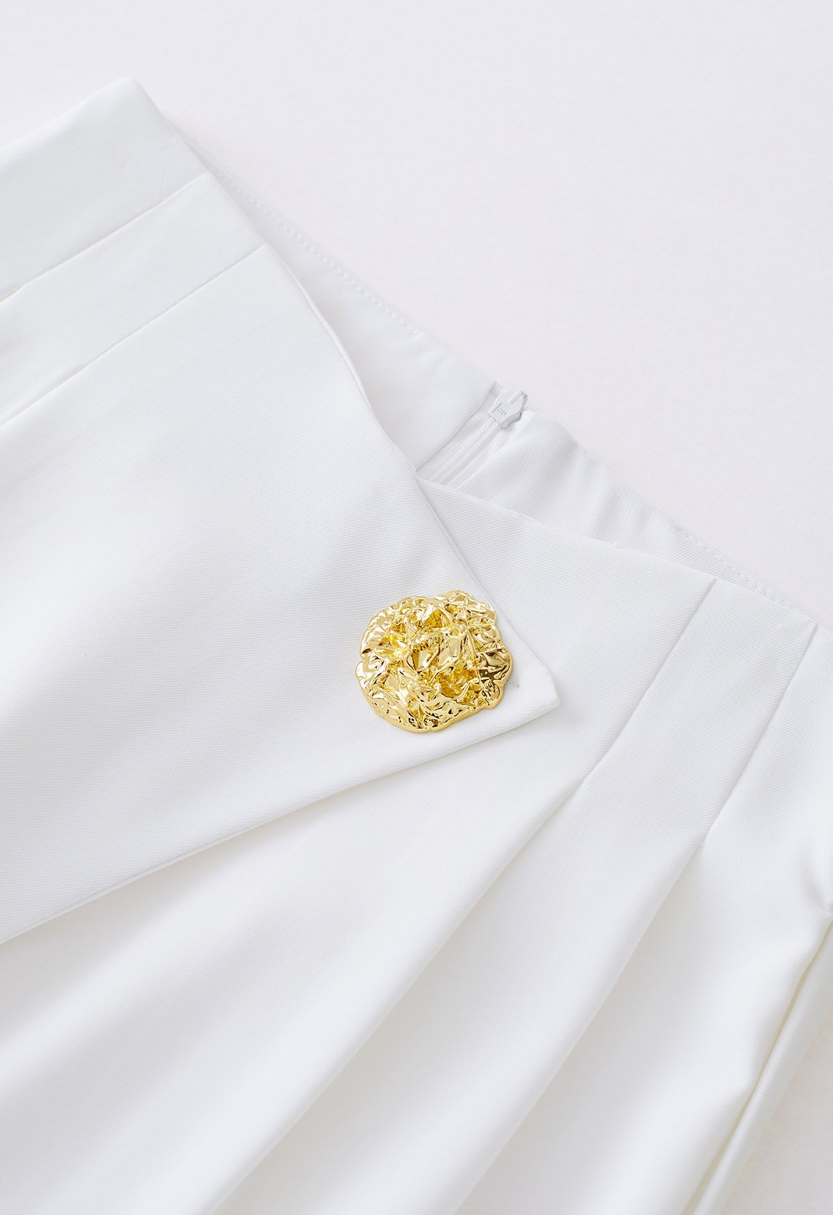 Pantalones rectos de cintura cruzada con botones dorados en blanco