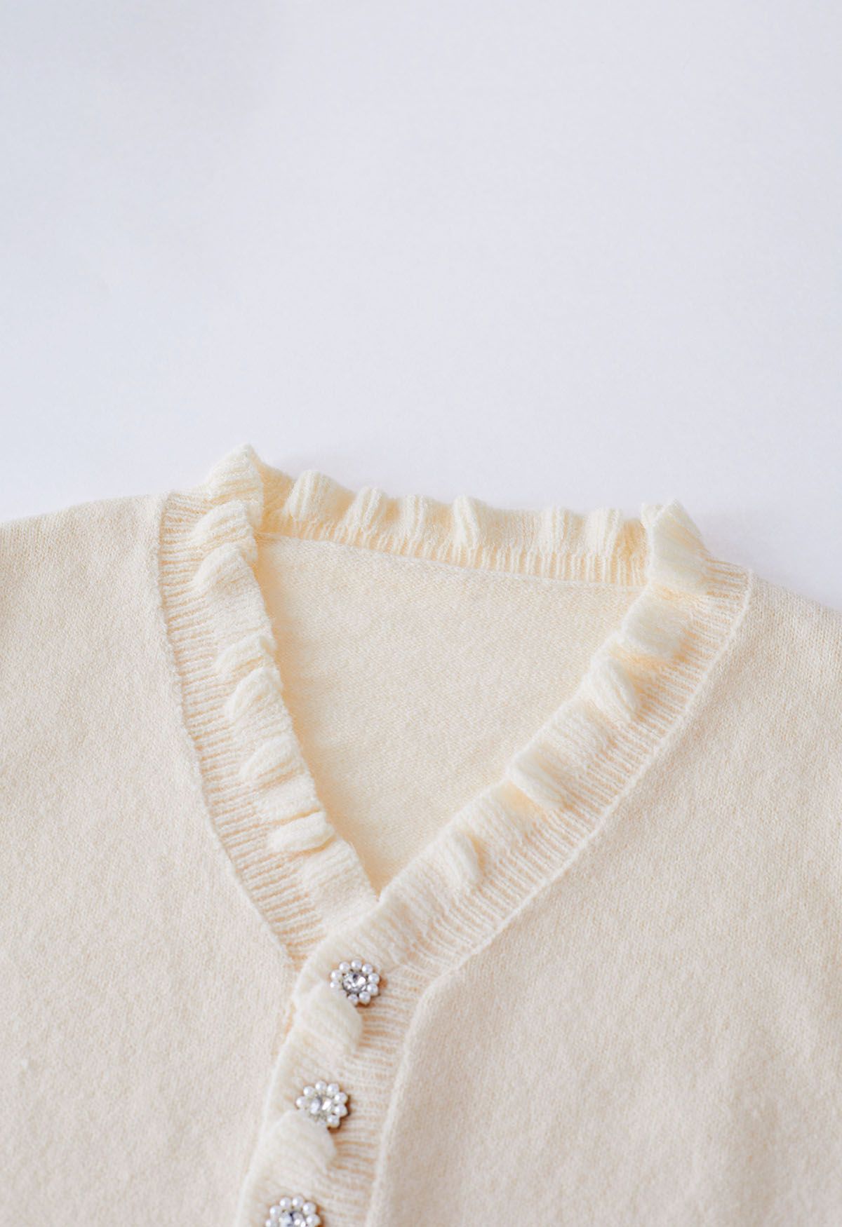 Suéter de punto con botones en la parte delantera y borde con volantes en color crema