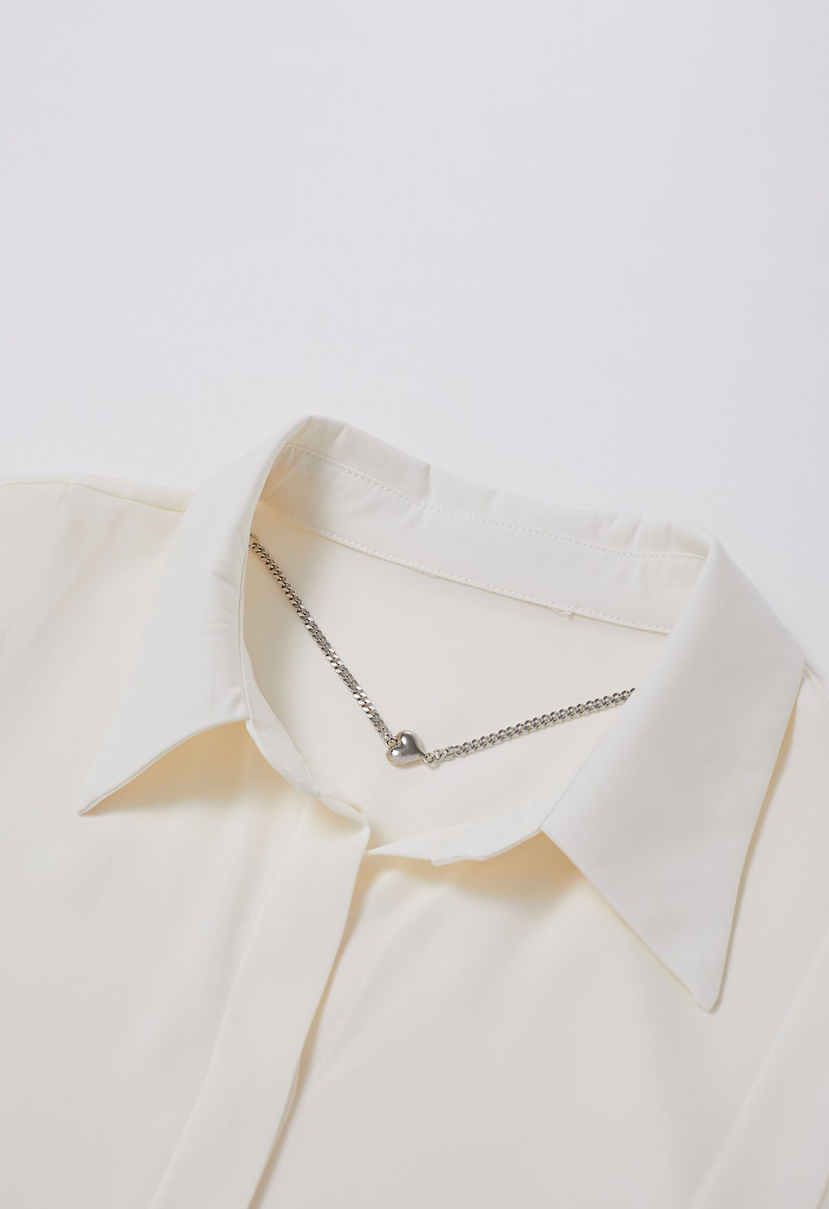 Camisa de raso con cuello en V y collar de corazones en color crema