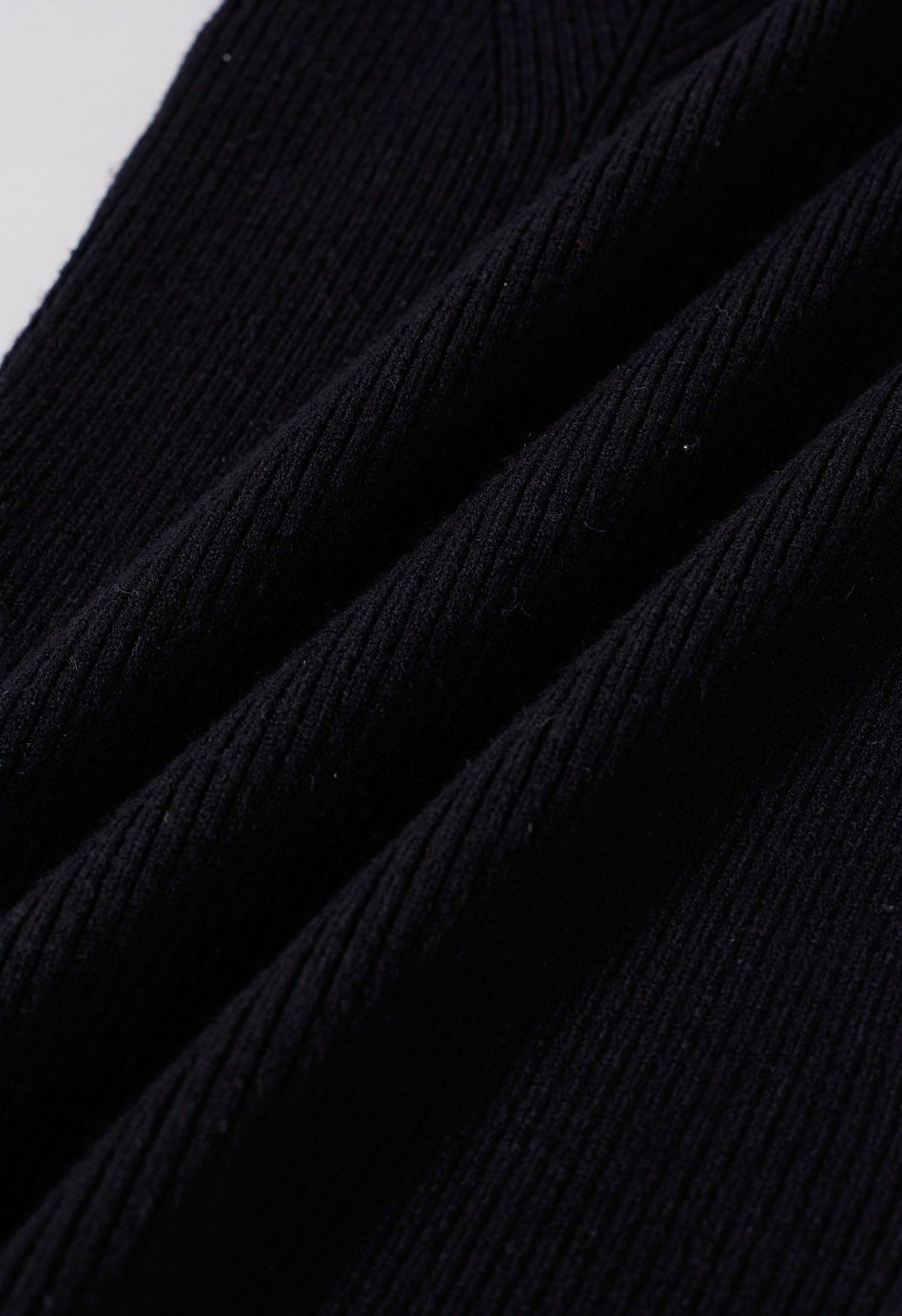 Top de punto con puños y ribete de plumas con escote ondulado en negro