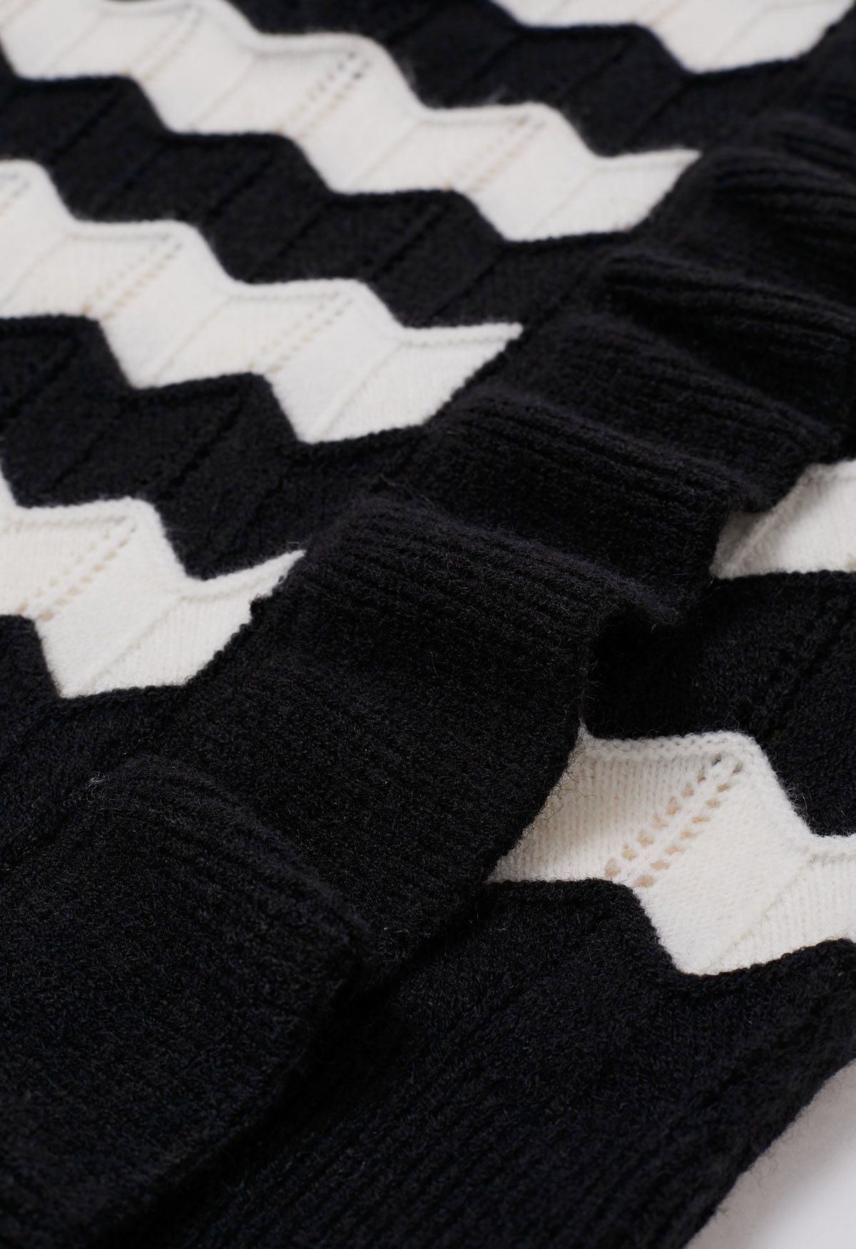 Suéter de punto con rayas onduladas y ribete de volantes en negro