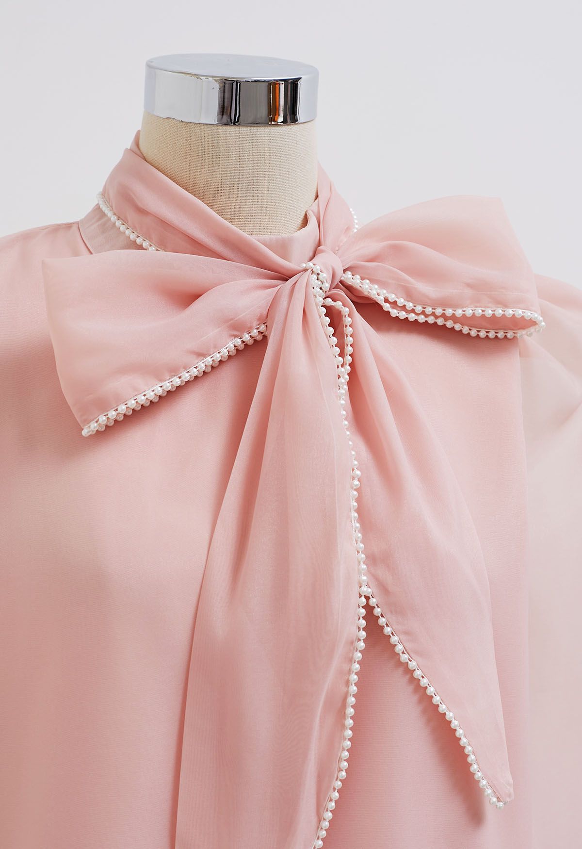 Camisa de manga abullonada con lazo nacarado en rosa