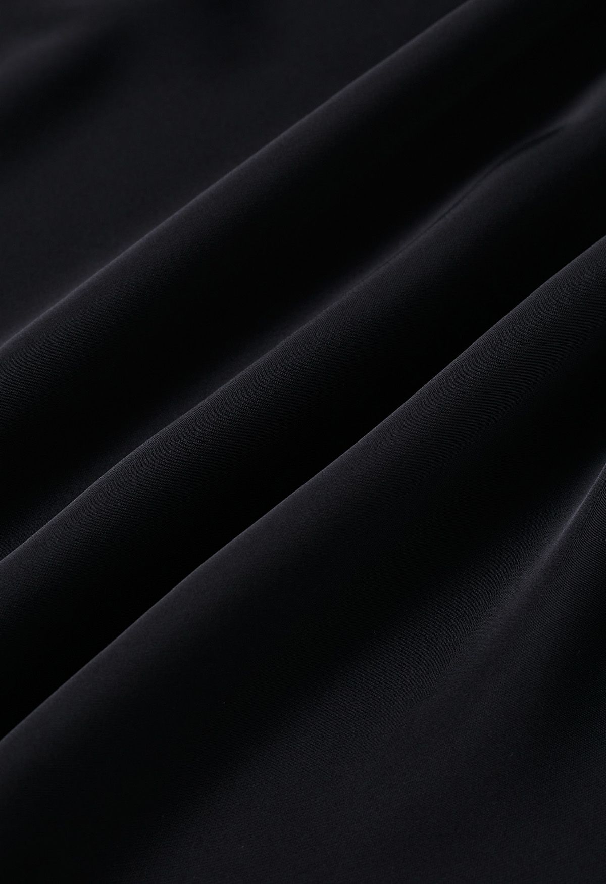 Top asimétrico de manga larga de satén fruncido en negro