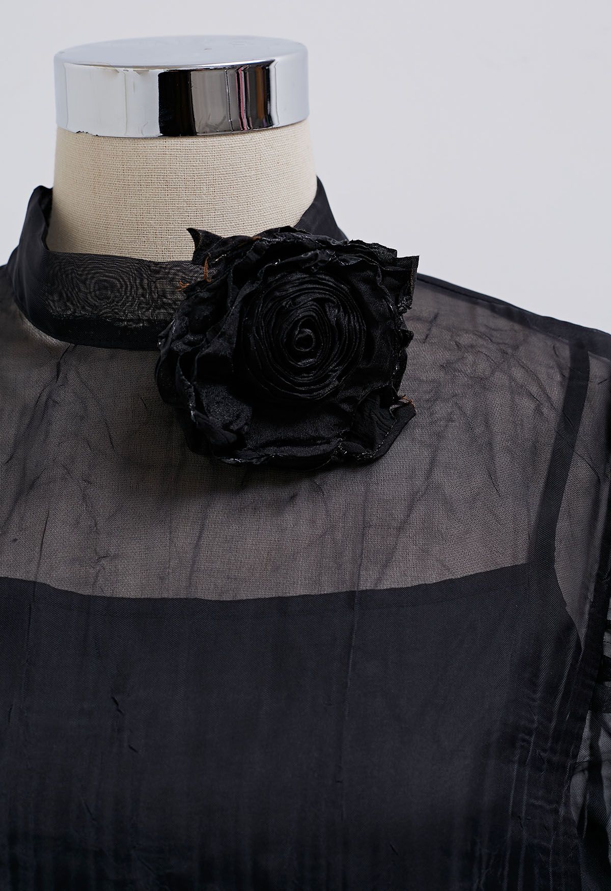 Top transparente con textura y manga abullonada en negro con broche de rosas