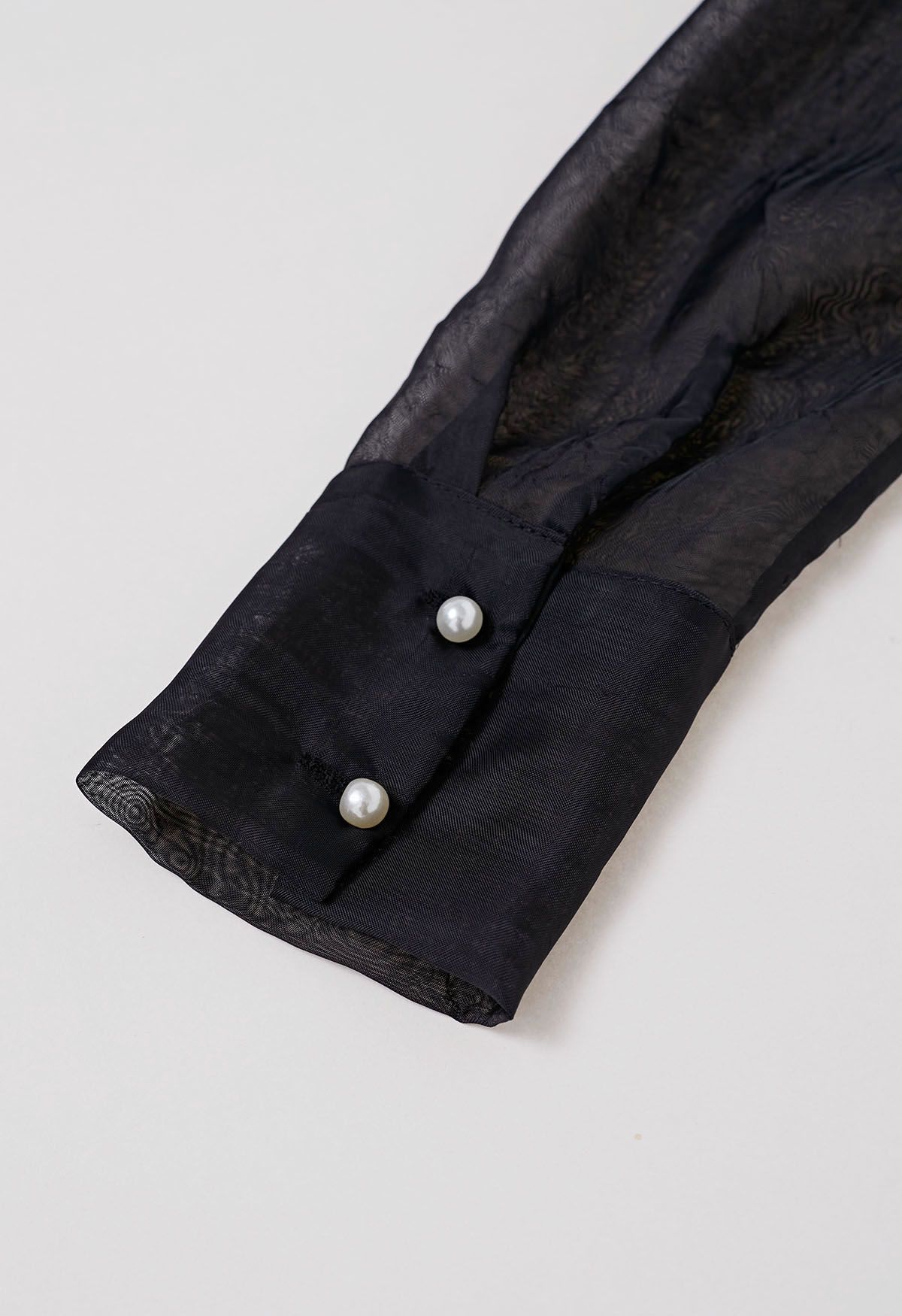 Top transparente con textura y manga abullonada en negro con broche de rosas
