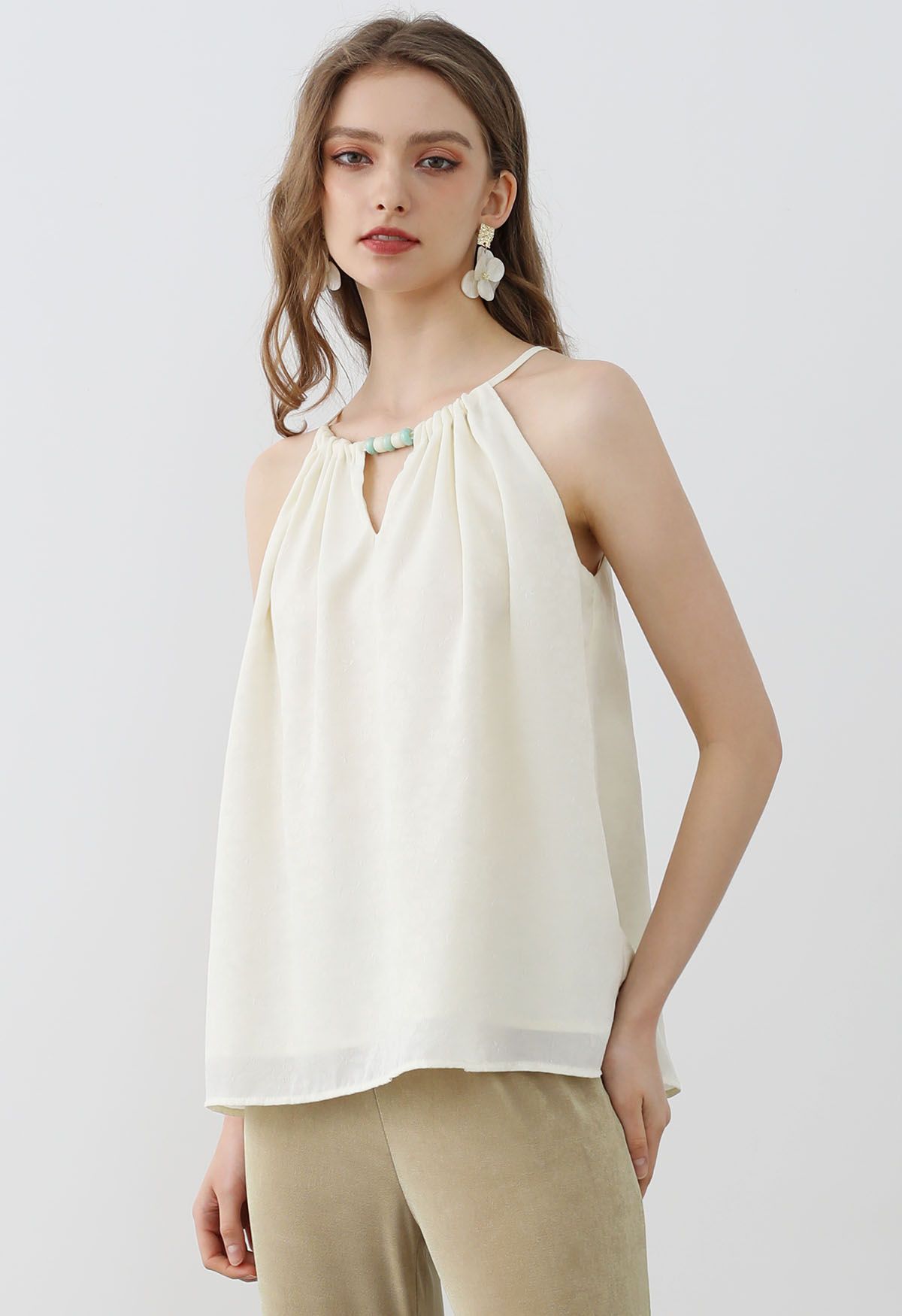 Top de jacquard floreado con cuello halter y pedrería en color crema