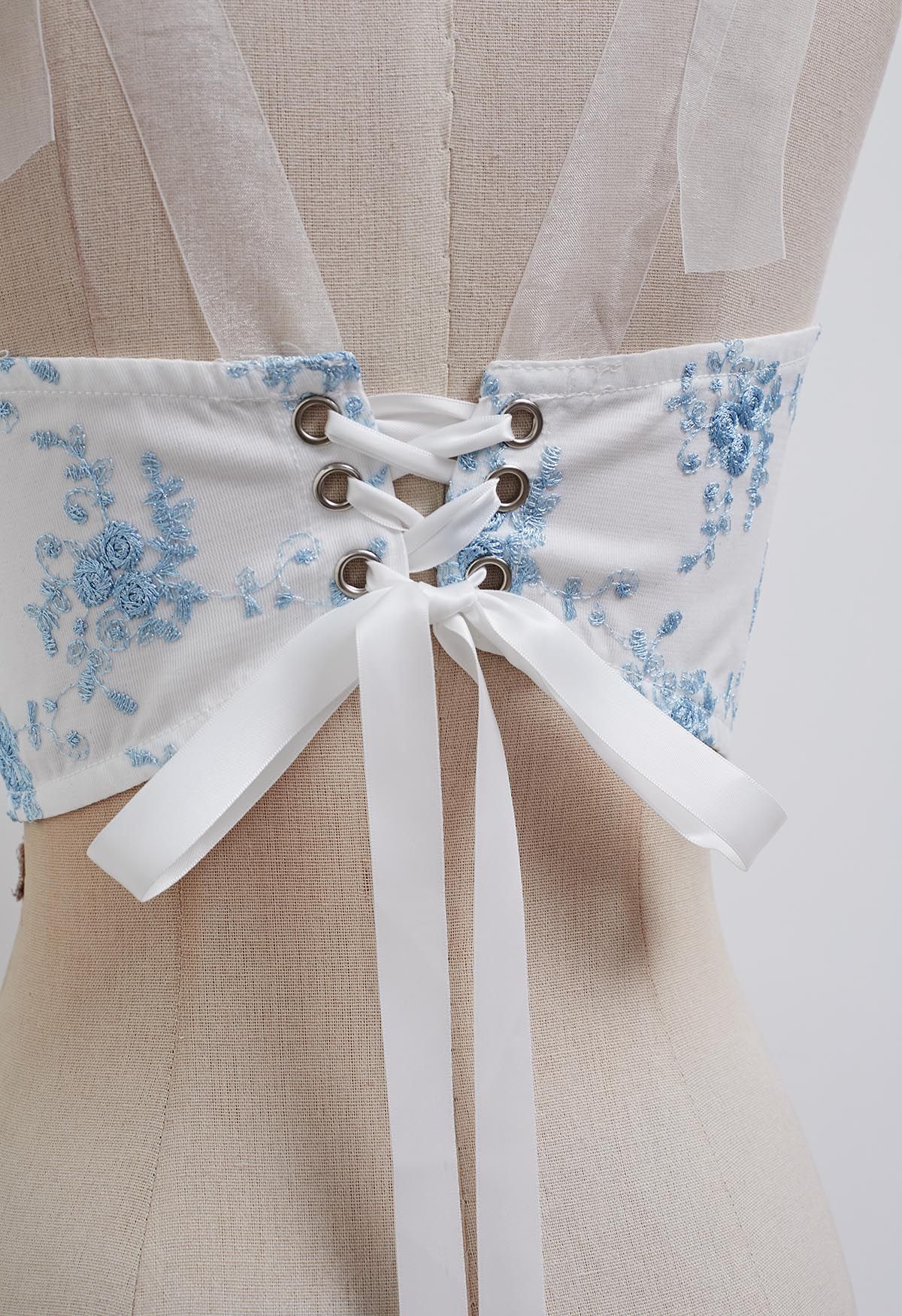 Top tipo bustier con tirantes y bordado floral azul en blanco