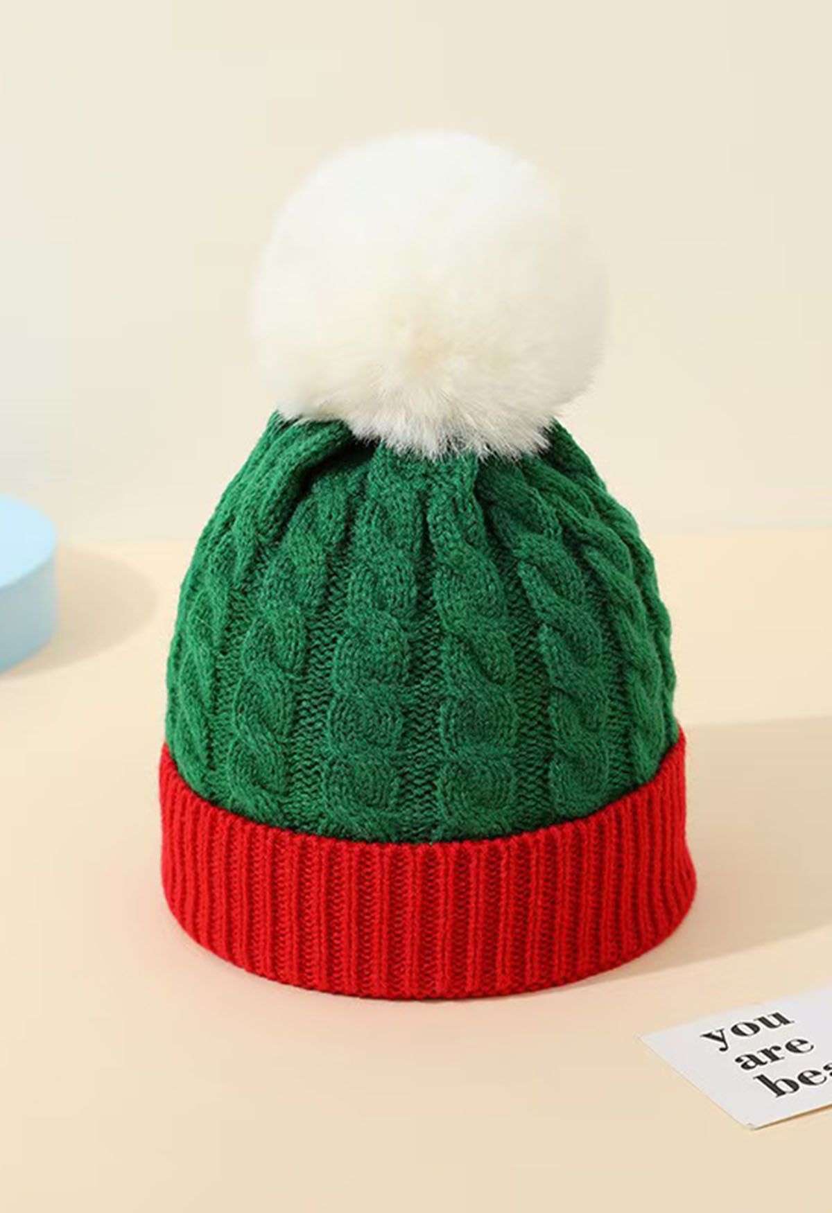 Gorro de punto trenzado con pompones peludos en color verde