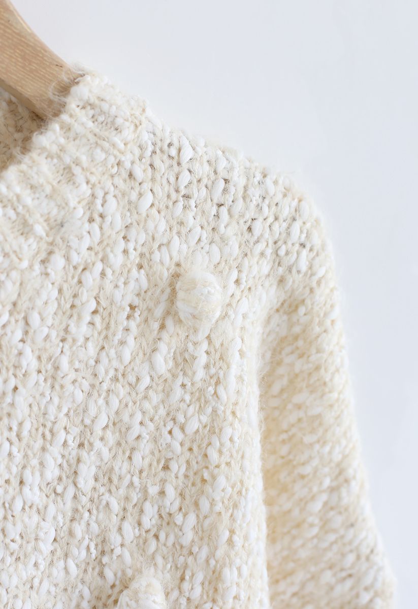 Suéter corto de punto difuso decorado con pompones en color crema