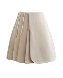 Minifalda con solapa plisada decorada con cadena de cristales en color arena
